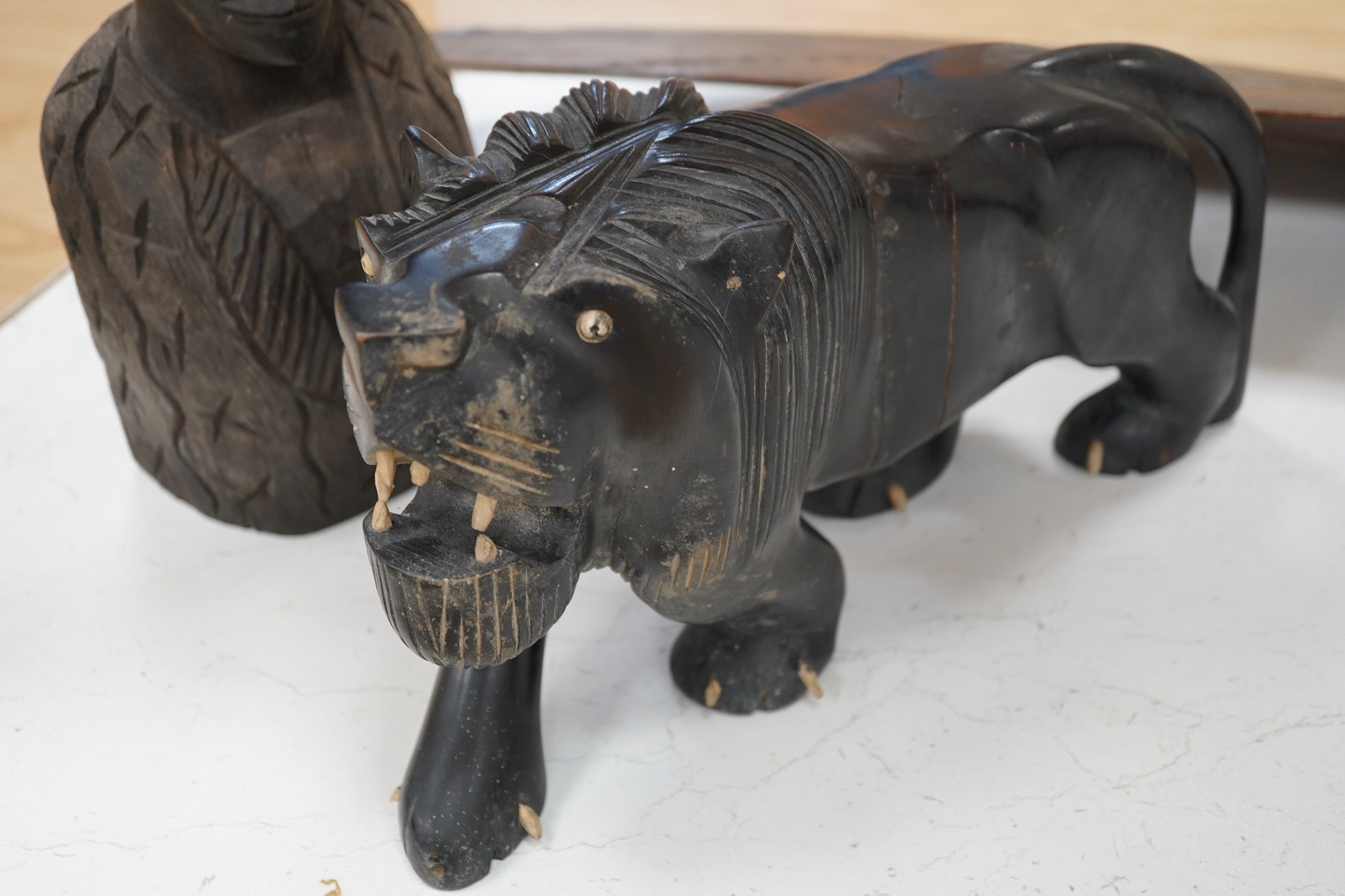 An African hardwood carving of a bust, 41cm high and an ebony Indian carving of a lion, 35cm long, (2). Condition - fair